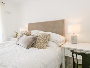 a bedroom with a white bed with pillows and a desk at Sandacre Cottage in Ulverston