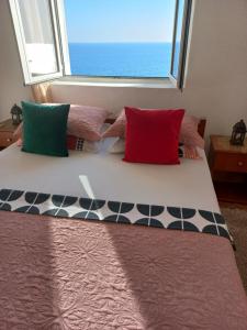 a bed with colorful pillows in a room with a window at Apartments Antigona Old Town in Ulcinj