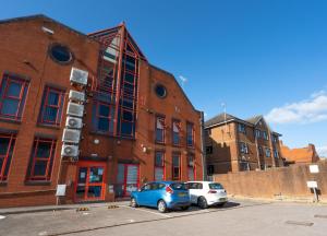 zwei Autos auf einem Parkplatz vor einem Backsteingebäude in der Unterkunft Modern & Stylish Studio in Reading Centre in Reading