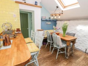 Una cocina y un comedor con mesa y sillas de madera. en Gull Cottage, en Bodorgan