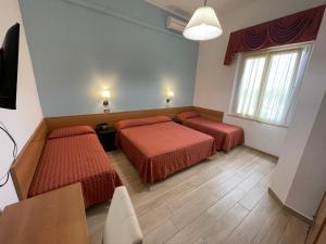um quarto de hotel com duas camas e uma mesa em Hotel Amelia em Fano