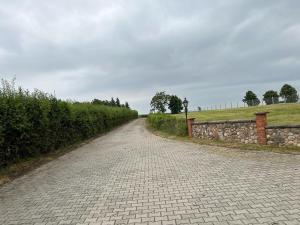 een geplaveide weg met een stenen muur en een veld bij Agroturystyka Trzy wieże in Bytom Odrzański
