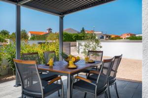 Une table et des chaises en bois sont disponibles sur la terrasse. dans l'établissement Ascolana Holiday Home, à Šibenik
