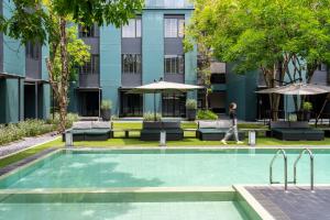 a person walks by a swimming pool in front of a building at Theatre Residence in Bangkok
