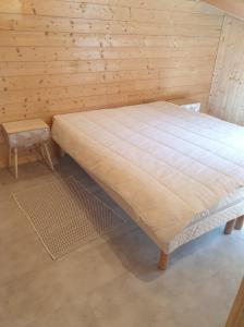 een bed in een kamer met een houten muur bij WhispeRive Lodge - le vert aux bords de rive in Le Bourg-dʼOisans