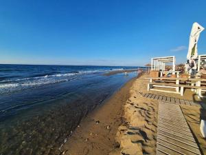 a sandy beach with benches and the ocean at M&M Modern Seaside Apartments Ammoudara Heraklion in Gázion