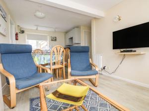 a living room with two chairs and a flat screen tv at Surf Watch - Mount Brioni in Downderry