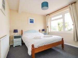 a bedroom with a bed and a window at Surf Watch - Mount Brioni in Downderry