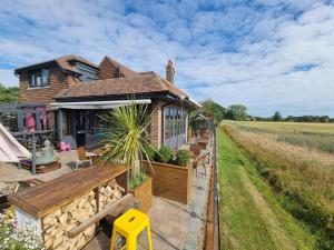 ein Haus mit einer Veranda neben einem Feld in der Unterkunft Varr House @ Meadow View in Woodmancote