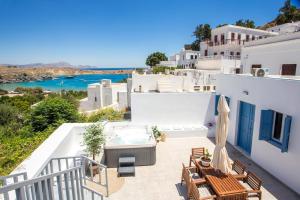 a balcony with a hot tub and tables and chairs at Villa Euphrosyne in Líndos