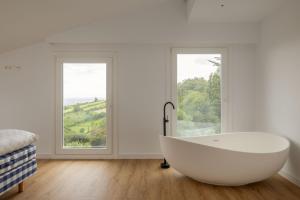 a white bath tub in a room with two windows at Hotel Boutique Berazadi Berri in Zarautz