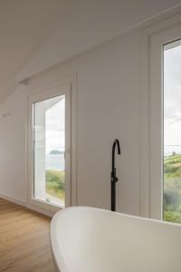 a white room with a tub and two windows at Hotel Boutique Berazadi Berri in Zarautz