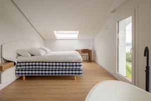 a white bedroom with a bed and a window at Hotel Boutique Berazadi Berri in Zarautz