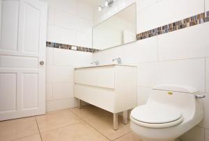 a white bathroom with a toilet and a sink at Diamond Gem Residence in Koolbaai