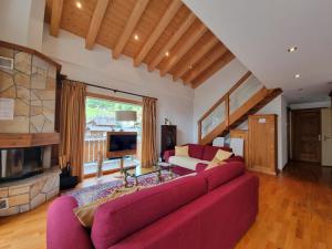 a living room with a red couch and a fireplace at Chalet Haus Perla in Saas-Fee