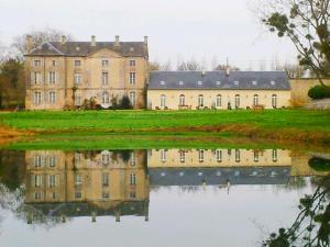 Una casa antigua con su reflejo en un cuerpo de agua en L'Orangerie du Grand Jardin, en Condé-sur-Seulles