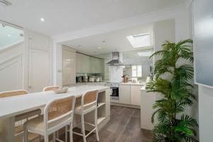 a kitchen with white cabinets and a table and chairs at GuestReady - Modern Apt in Chelsea with a Terrace in London