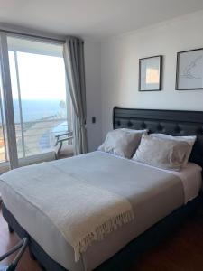a bedroom with a large bed with a large window at Departamento studio con exquisita vista in Viña del Mar