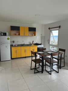 a kitchen with a table and chairs and yellow cabinets at Hostel Los Cormoranes in Ushuaia