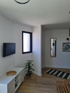 a living room with white walls and a tv at Location LA BELLE - LA ROCHELLE B in La Rochelle