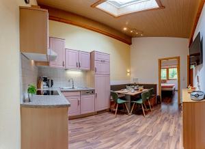 a kitchen with pink cabinets and a table with chairs at Landhaus Volderau in Neustift im Stubaital