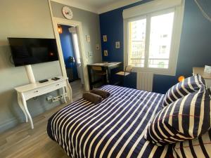a bedroom with a striped bed and a television at Studio Confort Lorient Nouvelle Gare Hypercentre in Lorient