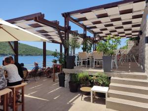 people sitting at tables on a patio with a view of the water at Suntime Villаs in Tivat