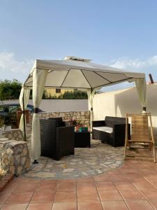 a patio umbrella with a couch and chairs under it at Case Vacanze Mio Sogno in Favignana