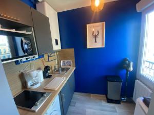 a kitchen with a blue wall and a sink at Studio Confort Lorient Nouvelle Gare Hypercentre in Lorient