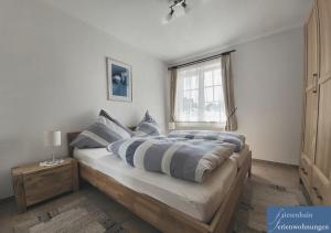 a bedroom with a bed with blue pillows and a window at Friesenhain Ferienwohnungen in Sankt Peter-Ording