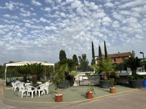 Un patio con mesas y sillas blancas y árboles. en Villa Patrizia, en Mostacciano