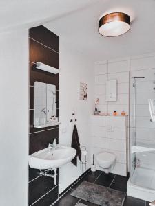 a white bathroom with a sink and a toilet at Holiday Home Alessia in Bollendorf