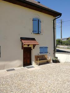 ein weißes Haus mit einer Bank und blauen Fenstern in der Unterkunft Studio à la campagne dans corps de ferme rénovée in Chancey