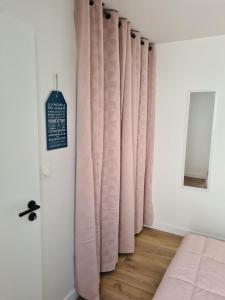 a bedroom with pink curtains and a wooden floor at Location LA REBELLE - LA ROCHELLE B in La Rochelle