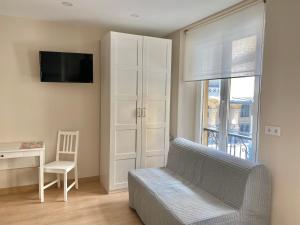 a living room with a couch and a desk and a window at Alojamientos Muelle de Gijón in Gijón