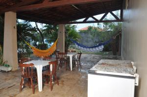 a patio with tables and chairs and a hammock at Cumbuco - Casa de praia com piscina e deck in Cumbuco