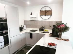 a white kitchen with a counter with a bowl of fruit at Salisbury Suite - Modern 2 bedroom flat with parking in Menai Bridge in Menai Bridge