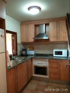 uma cozinha com armários de madeira e um forno com placa de fogão em PRECIOSO APARTAMENTO JUNTO AL MAR em Isla Canela