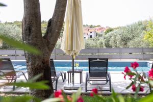 a patio with chairs and an umbrella and a pool at Apartments Tina Stinjan in Pula