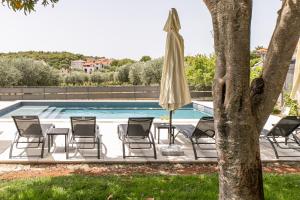 a group of chairs and an umbrella next to a pool at Apartments Tina Stinjan in Pula