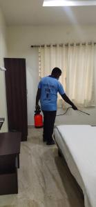 a man is making a bed in a room at Arihanth Inn in Vellore