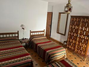 2 camas en una habitación de hotel con espejo en Hostal Rural Poqueira en Capileira