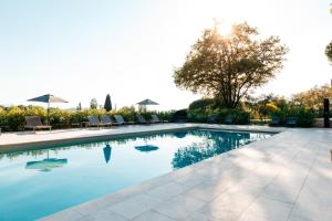 una piscina con sillas y sombrillas en un patio en Domaine Perréal Les Chambres en Gargas