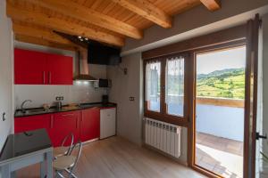 a kitchen with red cabinets and a large window at La besñada in Cangas de Onís