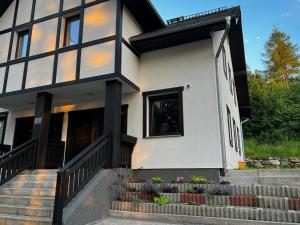 a white and black house with stairs and flowers at ApartaLala, Apartament z ogrodem in Karpacz