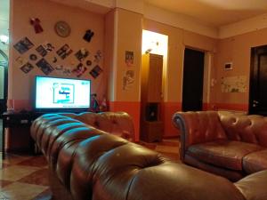 a living room with a leather couch and a television at Museum Hostel in Tbilisi City