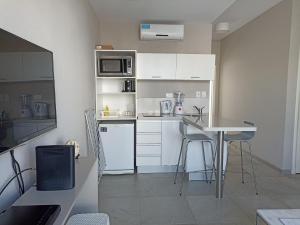 a small kitchen with white cabinets and a table at Vizion Suites by D&G in Carilo