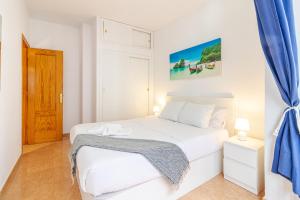 a bedroom with a white bed and a blue curtain at Lovely Flat Santa Catalina Park in Las Palmas de Gran Canaria