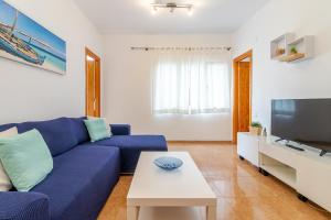 a living room with a blue couch and a tv at Lovely Flat Santa Catalina Park in Las Palmas de Gran Canaria