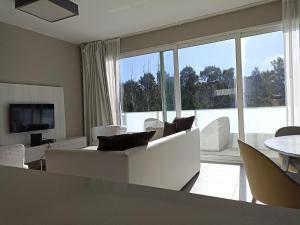 a living room with white furniture and a large window at Vizion Suites by D&G in Carilo